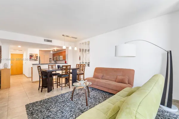 a living room with furniture potted plant kitchen view and a dining table
