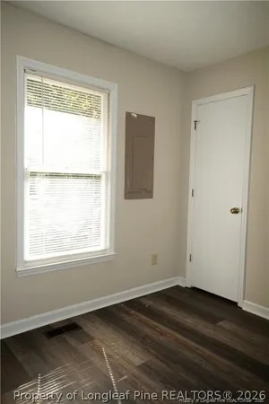 a view of an empty room with wooden floor and a window