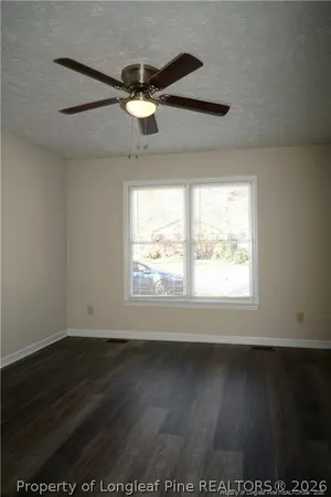 an empty room with wooden floor fan and windows