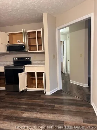 a view of a kitchen with stainless steel appliances wooden floor and cabinets