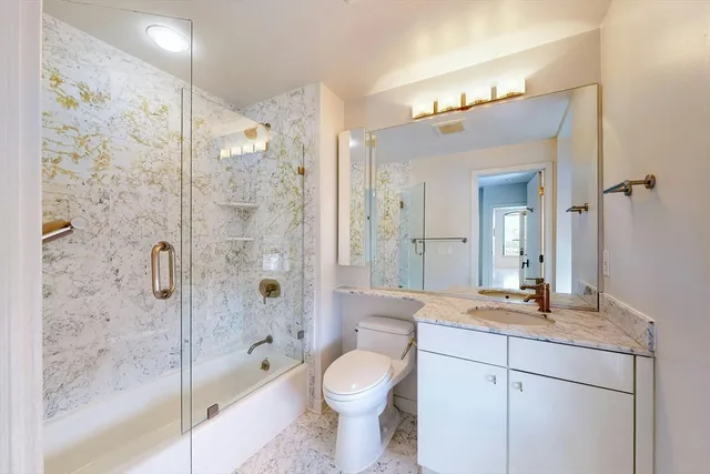 a bathroom with a granite countertop sink toilet and shower