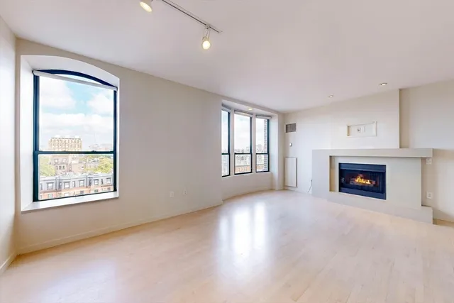 an empty room with windows and fireplace
