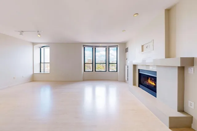 an empty room with windows and fireplace
