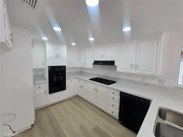 a kitchen with granite countertop a stove top oven and cabinets