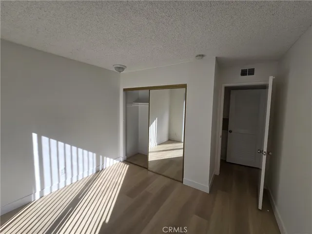 a view of a hallway with wooden floor and a bathroom