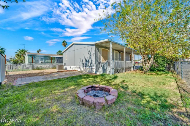 a backyard of a house with table and chairs plants and large tree
