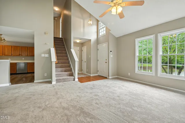 an empty room with chandelier fan and windows
