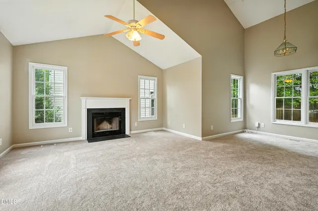 an empty room with windows and fireplace