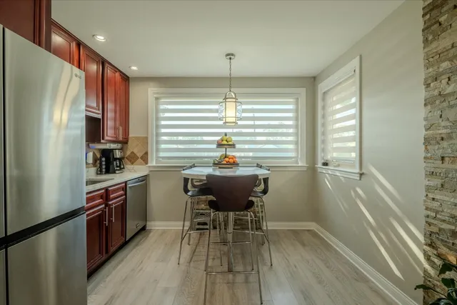 a kitchen with stainless steel appliances wooden floor dining table and chairs