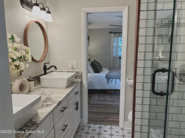 a bathroom with a granite countertop sink a mirror and shower