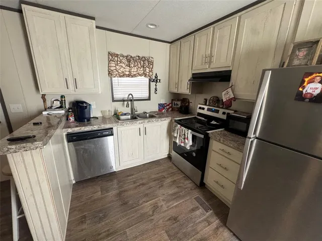 a kitchen with a sink a stove top oven a refrigerator and cabinets