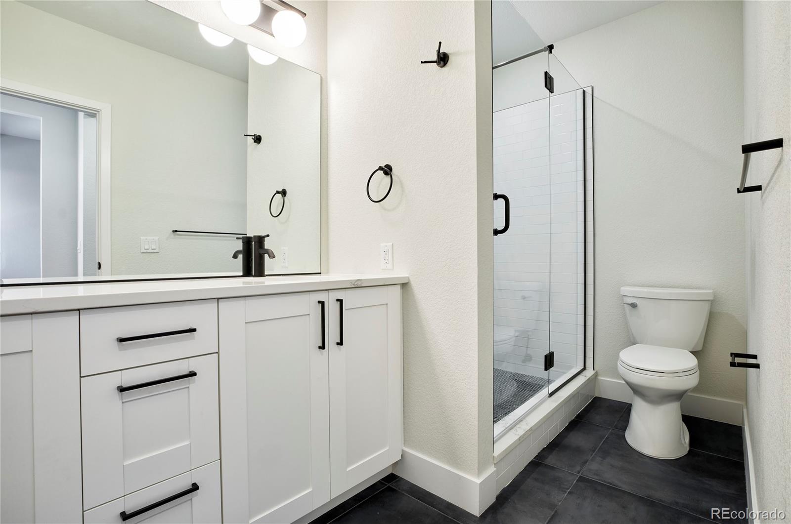 2951 East Evans Avenue Denver, CO 80210 - Photo 8 of 39 a bathroom with a granite countertop sink toilet a mirror a vanity and shower