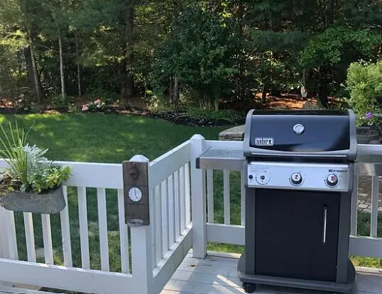 a view of a deck with a small yard and large trees