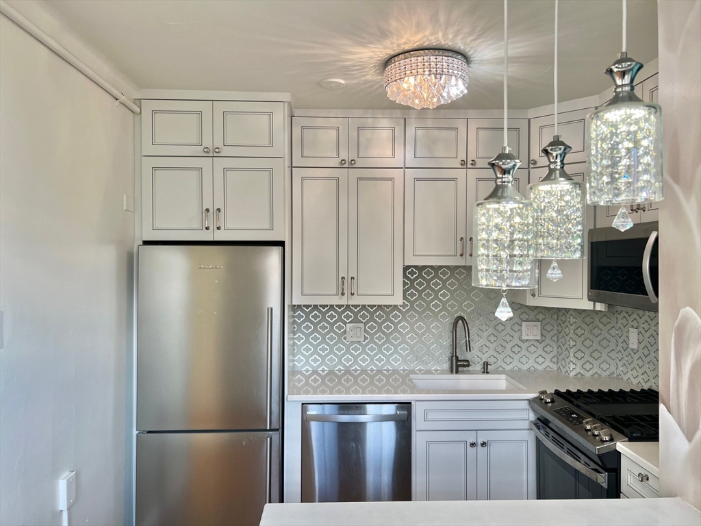 1454 Beacon Street, Unit 744 Brookline, MA 02446 - Photo 1 of 18 a kitchen with a refrigerator a sink and cabinets