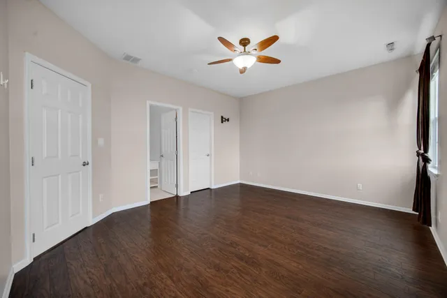 an empty room with wooden floor and chandelier fan