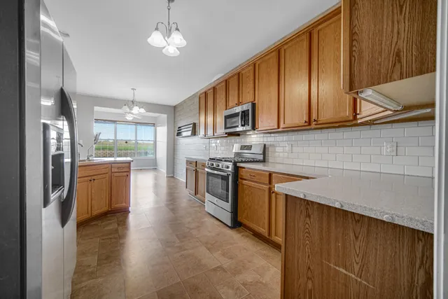 a kitchen with stainless steel appliances granite countertop a stove a sink dishwasher a refrigerator and a microwave oven