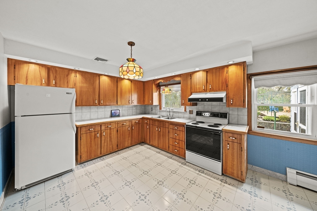 7 Cedarcrest Road Salem, MA 01970 - Photo 11 of 41 a kitchen with stainless steel appliances granite countertop a refrigerator a sink dishwasher a stove top oven and a dining table with wooden floor