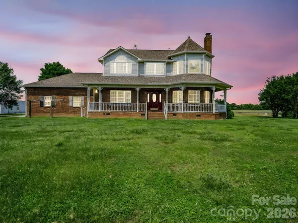 a view of a house with a big yard and large trees