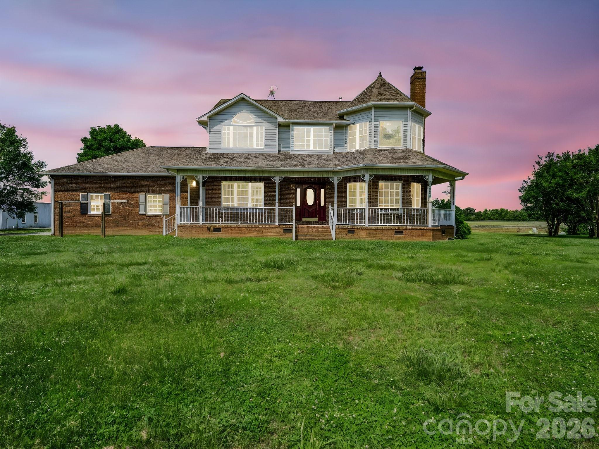 a view of a house with a big yard and large trees