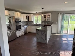 a kitchen with granite countertop a refrigerator stove top oven and sink