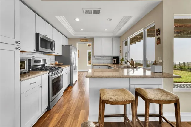 a kitchen with stainless steel appliances granite countertop table chairs sink and cabinets