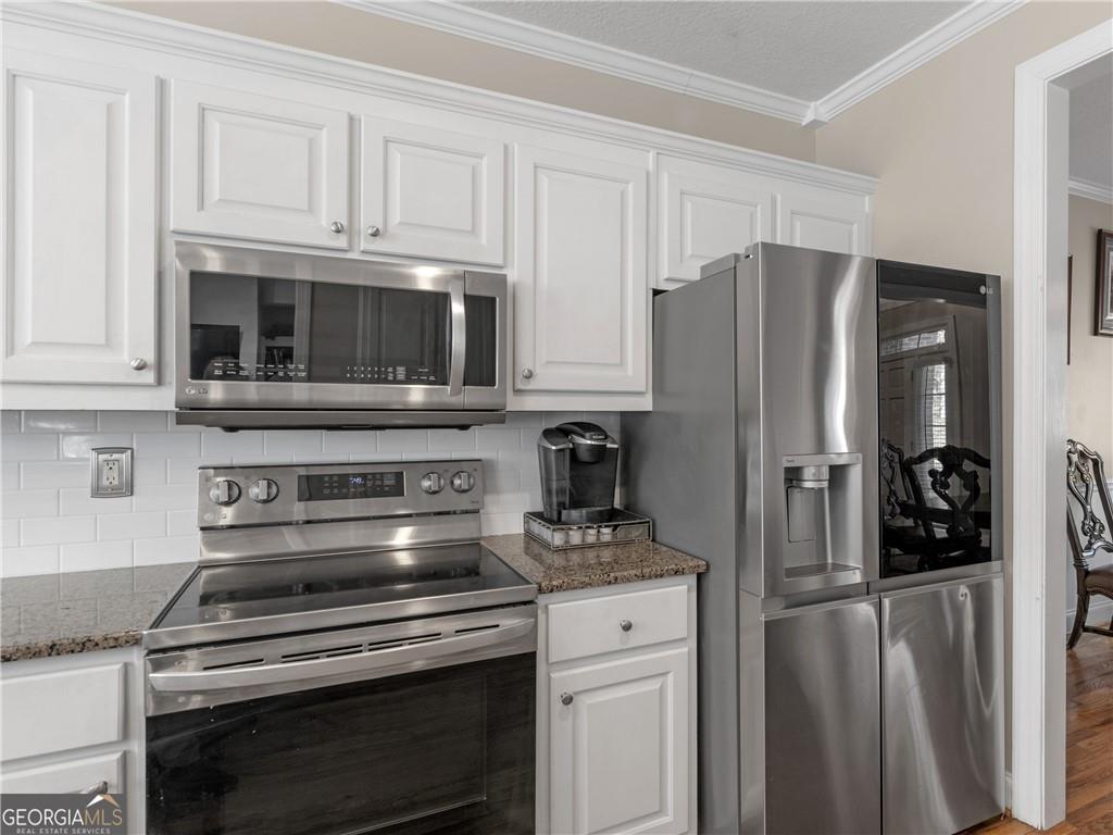 355 Parker Road Covington, GA 30014 - Photo 23 of 60 a kitchen with stainless steel appliances granite countertop a stove microwave and refrigerator