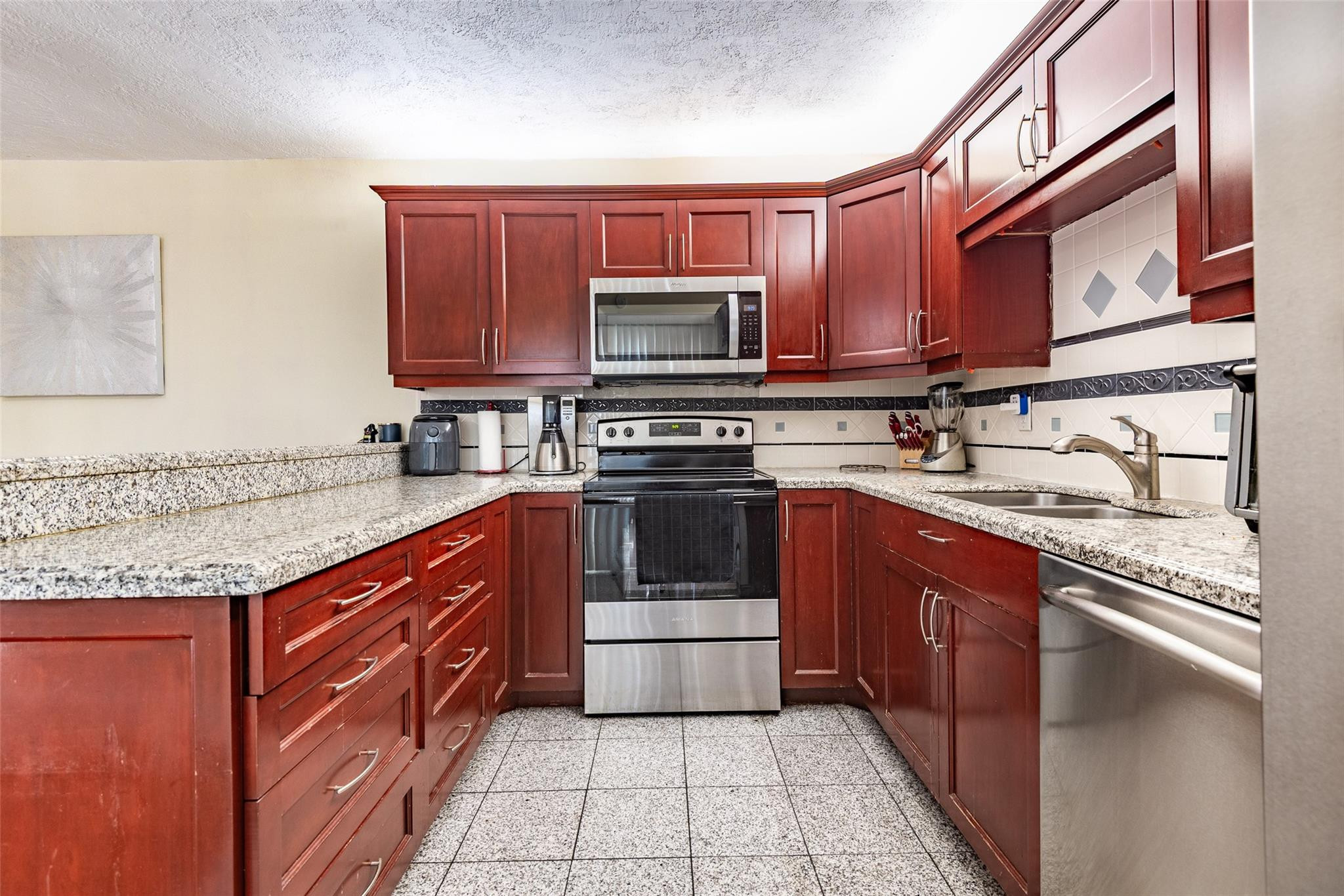 22208 Boca Rancho Drive, Unit D Boca Raton, FL 33428 - Photo 9 of 34 a kitchen with stainless steel appliances granite countertop a stove microwave and cabinets