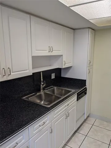 a kitchen with granite countertop white cabinets and a sink