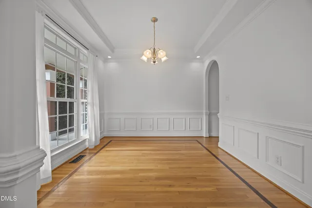 a view of an empty room with window and wooden floor