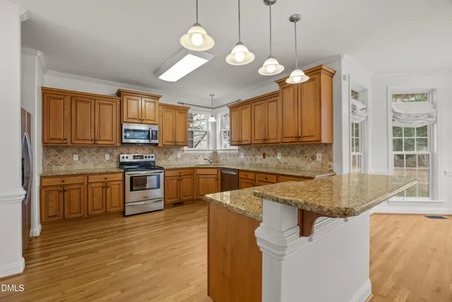 a kitchen with stainless steel appliances granite countertop wooden cabinets a stove top oven a sink and dishwasher