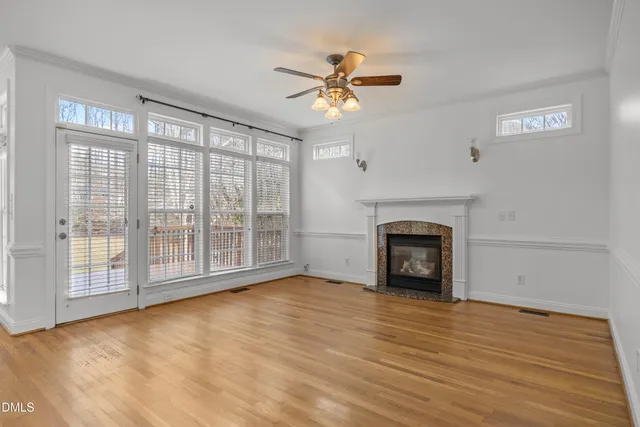 a view of an empty room with a window and wooden floor
