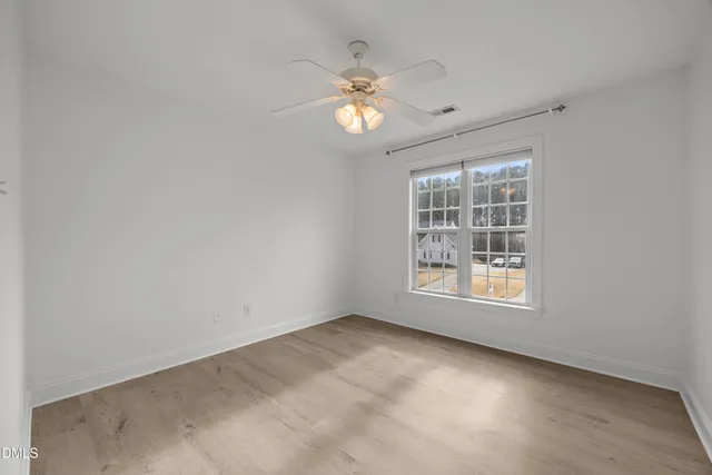 a view of an empty room with a chandelier fan