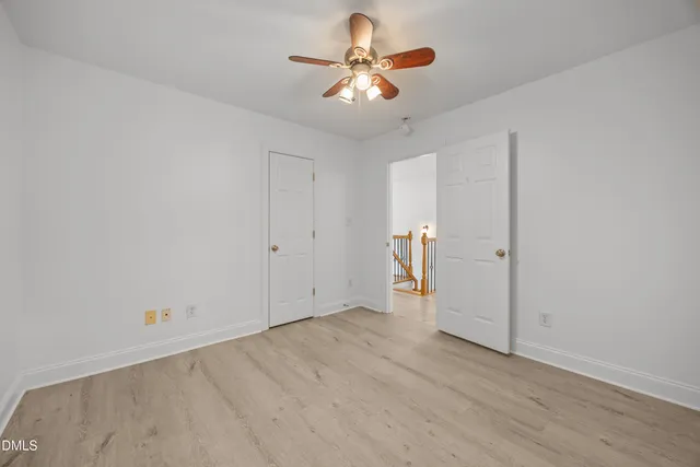an empty room with chandelier fan and windows