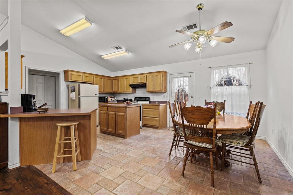 80 Campbell Road Sadler, TX 76264 - Photo 18 of 29 Kitchen with a kitchen bar, vaulted ceiling, a peninsula, brown cabinets, and electric appliances