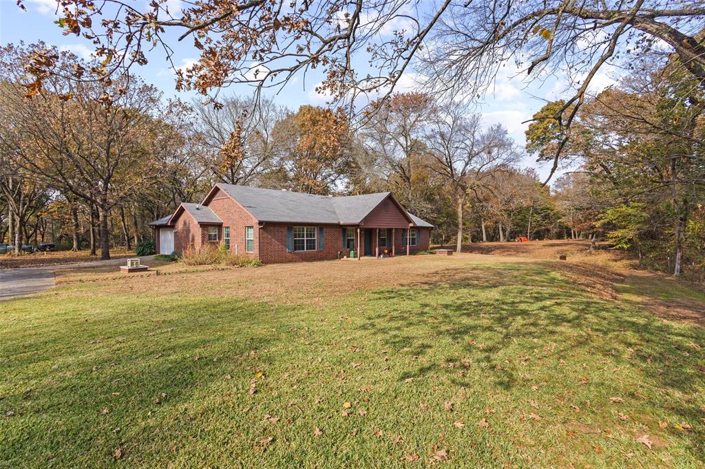 80 Campbell Road Sadler, TX 76264 - Photo 28 of 29 View of front elevation with a front yard, a garage, complete brick siding, asphalt driveway, flag pole and covered porch