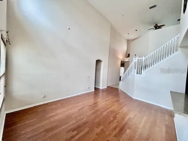 a view of an empty room with wooden floor and stairs