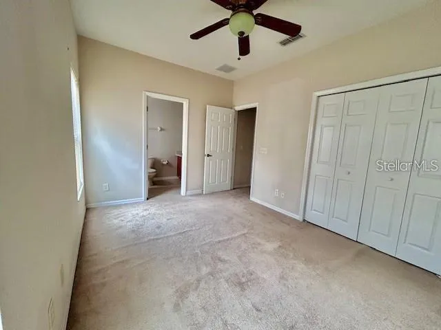 an empty room with a ceiling fan and closet area