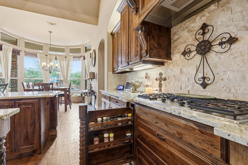 406 Spurgin Road Lucas, TX 75002 - Photo 12 of 39 Kitchen featuring light stone counters, stainless steel gas cooktop, tasteful backsplash, light wood-style flooring, and arched walkways