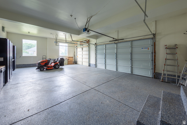 868 Braddock Lane Alpine, UT 84004 - Photo 53 of 64 Spacious garage featuring a durable epoxy-coated floor, dual overhead garage doors, built-in cabinetry with a wood-finish countertop, and multiple windows providing natural light