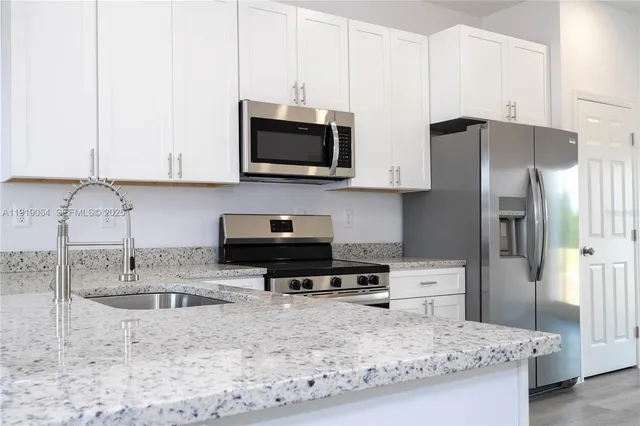 a kitchen with stainless steel appliances granite countertop a sink a stove and a refrigerator