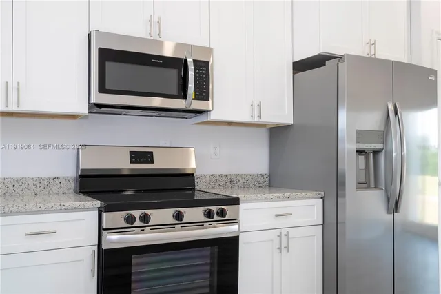 a kitchen with stainless steel appliances granite countertop a refrigerator stove and microwave