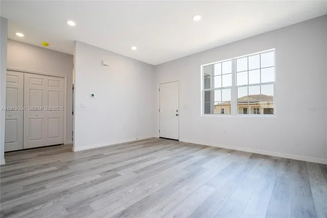 an empty room with wooden floor and windows