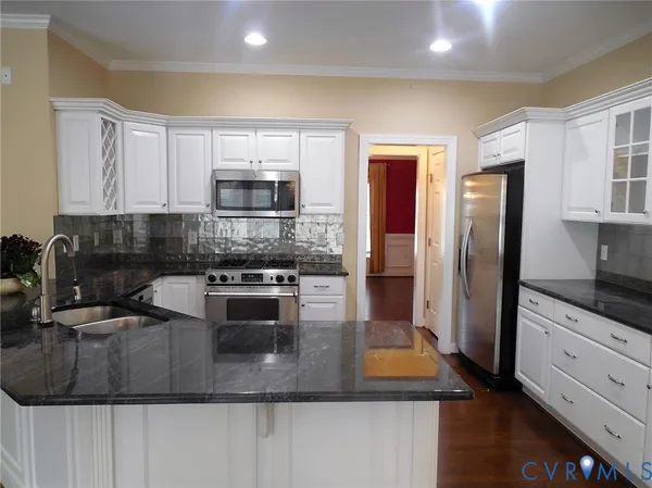 a kitchen with stainless steel appliances granite countertop a stove a sink and a refrigerator