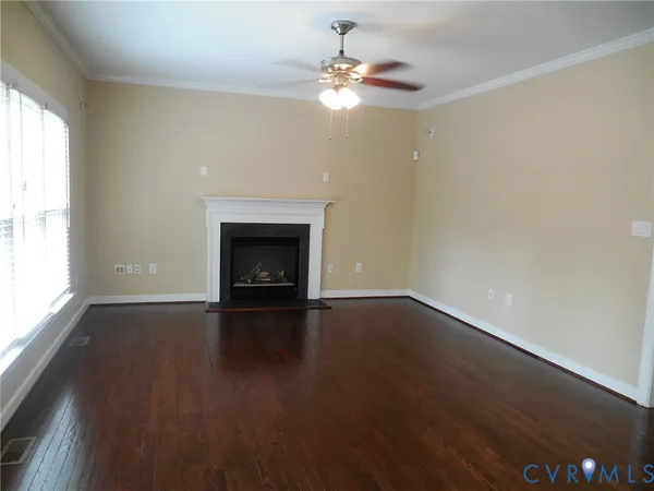 an empty room with wooden floor fireplace and windows