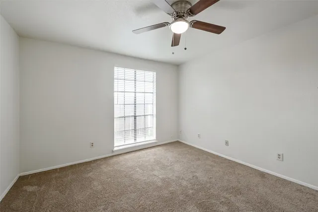 an empty room with chandelier fan and windows