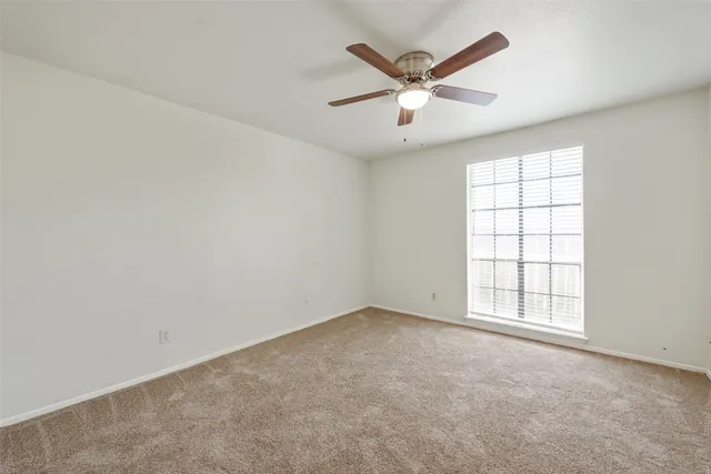an empty room with a window and a fan