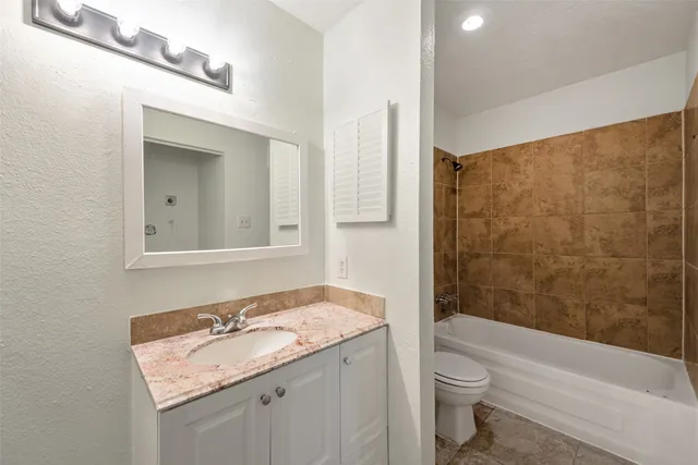 a bathroom with a granite countertop sink a toilet and shower