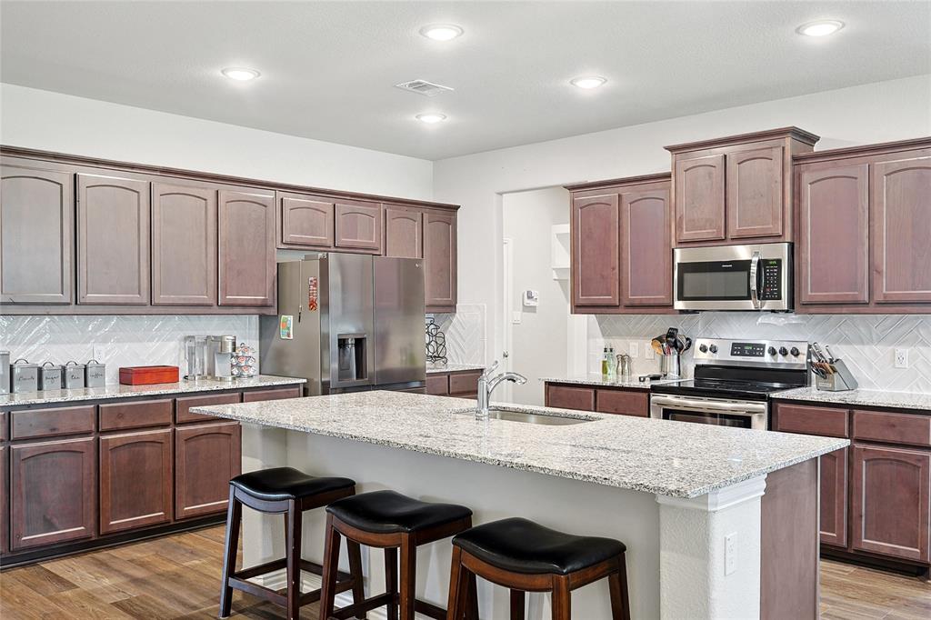 808 Feather Edge Drive Springtown, TX 76082 - Photo 13 of 40 a kitchen with stainless steel appliances granite countertop a sink a stove a microwave a refrigerator and cabinets