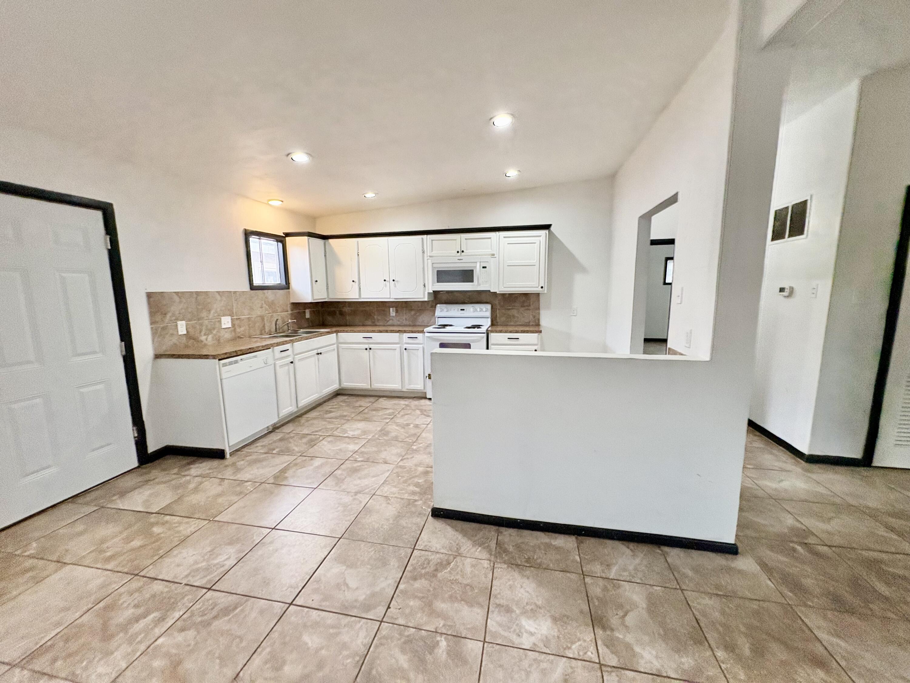 4403 44th Street Lubbock, TX 79414 - Photo 7 of 25 a kitchen with granite countertop a sink and white cabinets