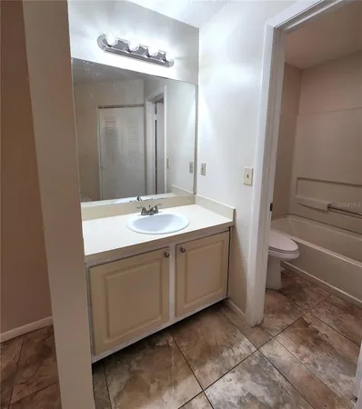 a spacious bathroom with a double vanity sink a toilet and a mirror
